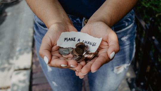 Hands offering coins and note that says 'make a change'