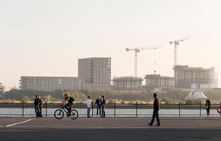 People walking and cycling by the docks in the context of emerging new development in the Royal Docks