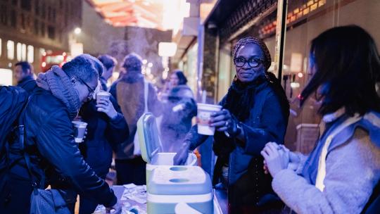 A community event on a high street where people are serving hot soup 