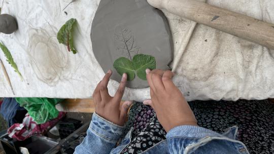 A girl making copies of leaves in clay during an art workshop 