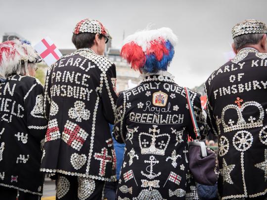 The backs of a group of Pearly Kings and Queens with elaborately decorated pearly jackets and clothing