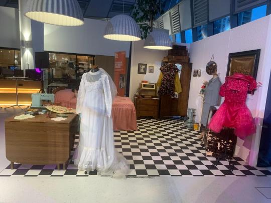 A display of a family bedroom with manequins wearing frilly dresses
