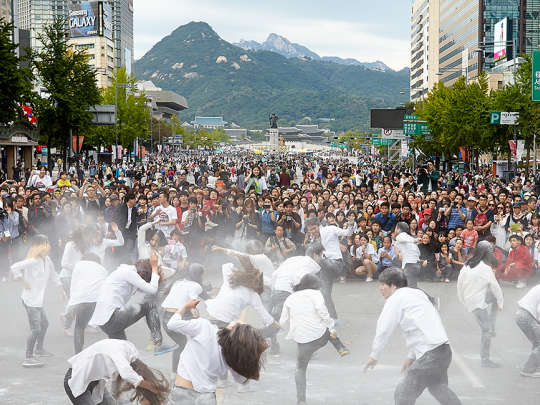Dancers performing on a road in front of a crowd