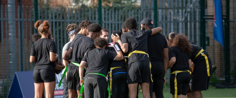 Young people discussing in a circle on a pitch