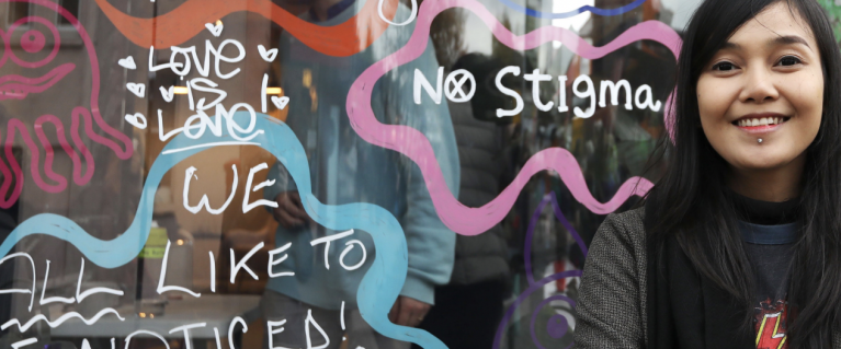 A person standing in front of a mirror that has messages against structural racism