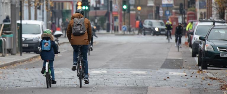 An adult cycling with their child on a London road