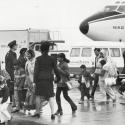 Ugandan and Asian people disembarking from a plane