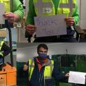 Volunteers wearing high-visibility vests hold up a piece of paper that reads ‘Thank you’