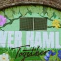 A mural of flowers and shades of green, painted on the wall under a railway arch. Text reads ‘Tower Hamlets Together’.