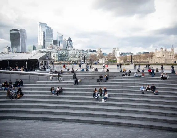 People sitting on steps at The Scoop, Tower Bridge