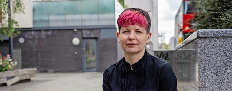 Zoë Garbett AM seated outside in London, staring stern faced at the camera