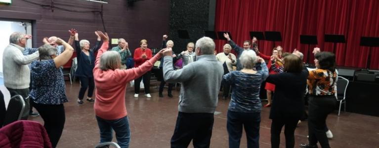 Several older people dance in a circle