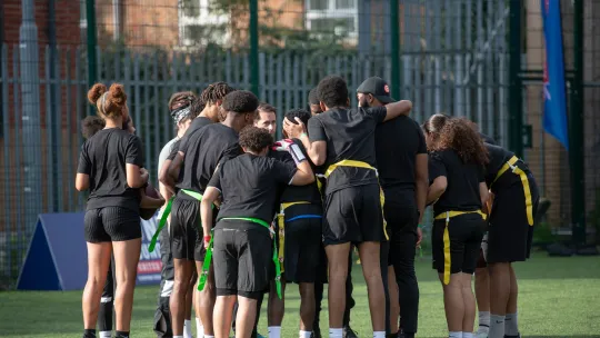 Young people discussing in a circle on a pitch