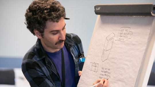 Man writes on a large paper note board