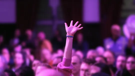 Image of a hand raised in the audience
