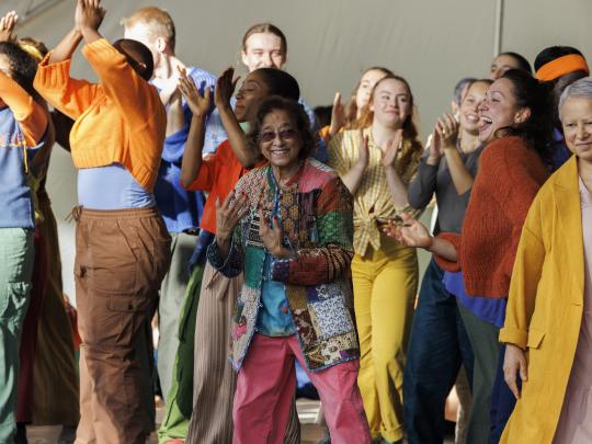 Volunteer performer smiles at the camera during Close To Home, The Mass Dance Event