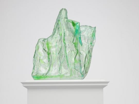 Green glass-like shroud over an invisible statue of a horse and rider, on a light grey plinth, side view
