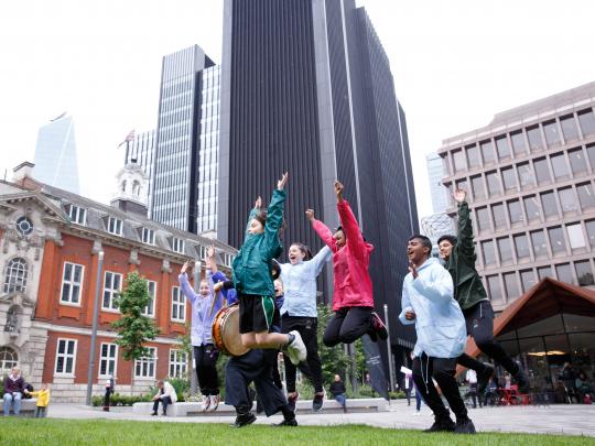 children jumping in the air with old and new buildings in the background
