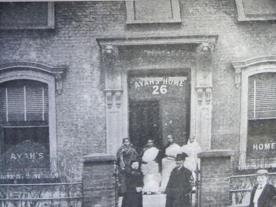 The front entrance of the Ayahs’ Home in Hackney in 1900. Four south asian women and three others stand in front of the building.