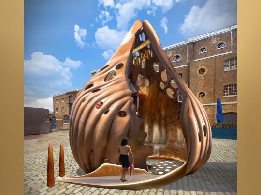 Computer-generated image with a traditional building in the background and a large, bronze colour sea shell, with a low ramp going into the centre, with a figure walking up the ramp. image with a traditional building in the background and a large, bronze colour sea shell, with a low ramp going into the centre, with a figure walking up the ramp.