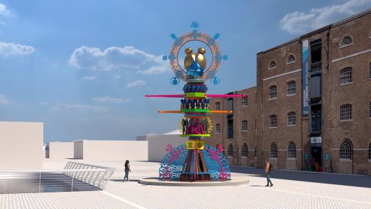 A computer generated image of a tall, assemblage of colourful and decorative elements, build into a tower or totem, that has overall sense of a female figure. It is in a public square with traditional victorian buildings in the background.