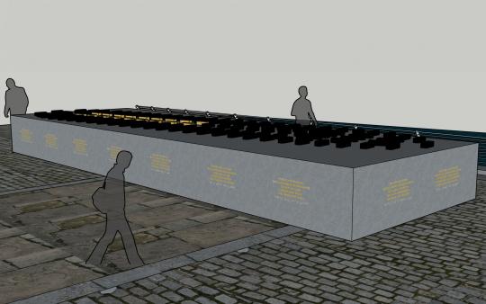 Side view of a computer-generated streetscape with cobbled street and a large grey, waist height, solid block, with gold coloured text around the side of the and on top of the grey block are smaller black blocks and a few gold coloured blocks.