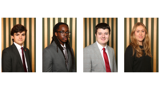 Four young people in suits smiling towards the camera