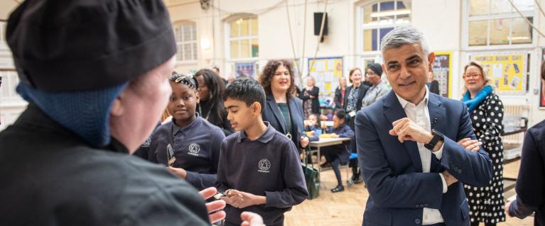 Mayor of London, Sadiq Khan, in a school canteen with canteen staff and students.