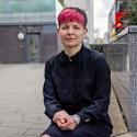 Zoë Garbett AM seated outside in London, staring stern faced at the camera