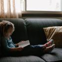 Child reading book on sofa. Photo by Josh Applegate on Unsplash. 