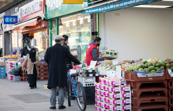 Man with a bike looking at a fruit and veg stall