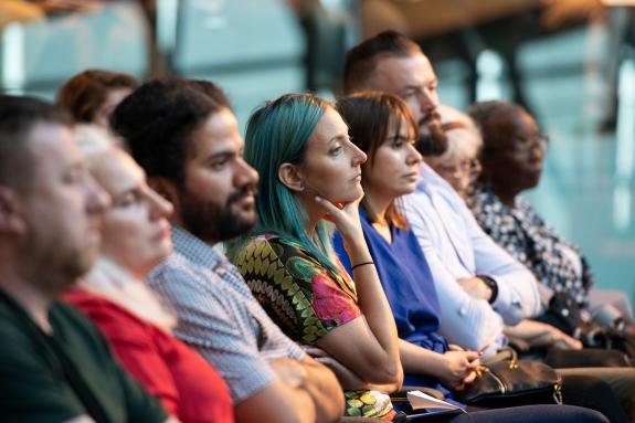 A row of people listening to a speaker